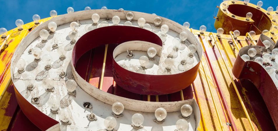 Close-up details of an old Las Vegas sign with vintage light bulbs, metal letters, and peeling paint.