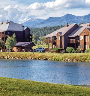 The exterior of WorldMark/Club Wyndham Pagosa, a Colorado timeshare resort surrounded by a lake and mountains.