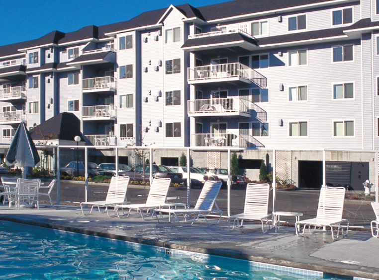 A pool surrounded by lounge chairs in front of the Wyndham Birch Bay Resort.