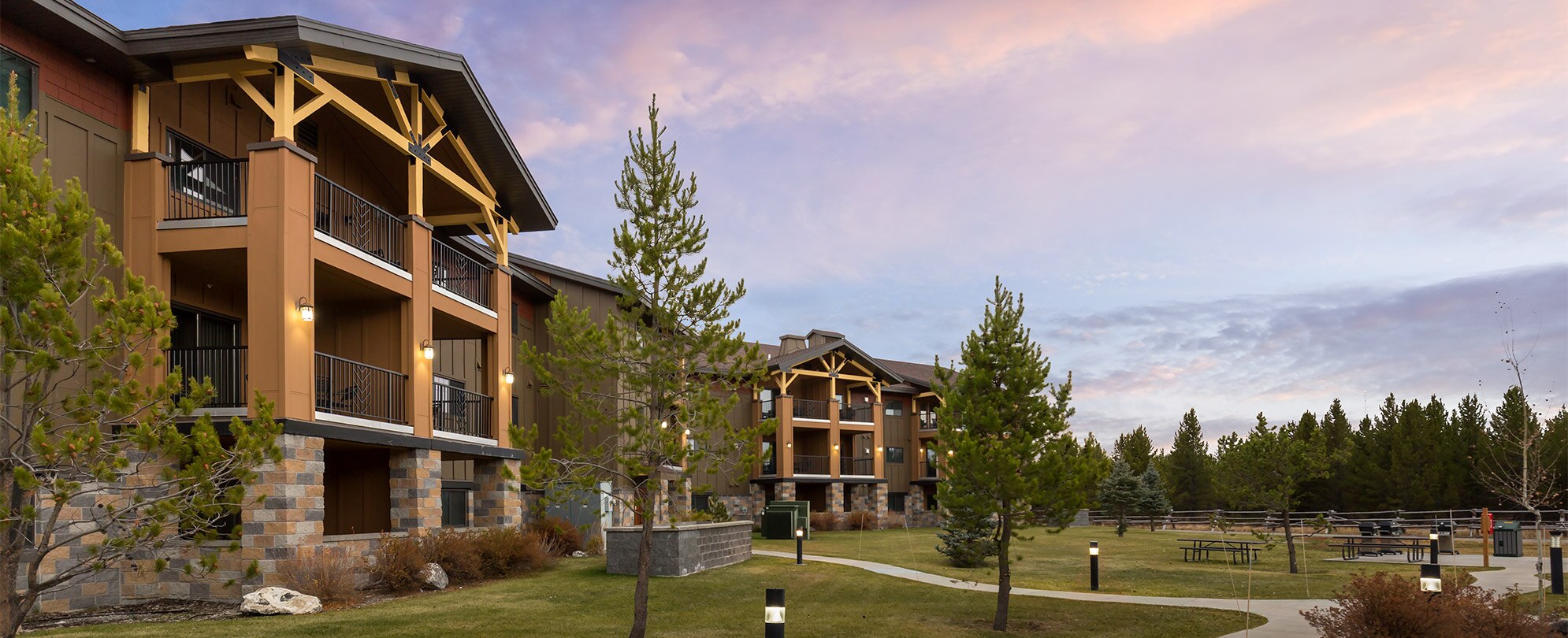 The exterior of a resort with trees and cloudy skies in Montana at the WorldMark West Yellowstone.