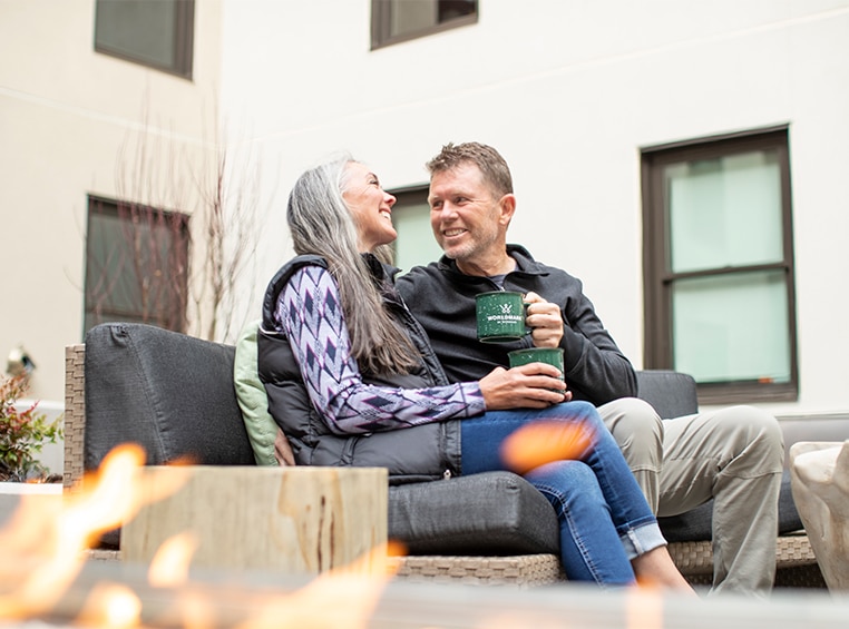 A couple looking at each other drinking coffee on the outdoor patio of a WorldMark by Wyndham resort.