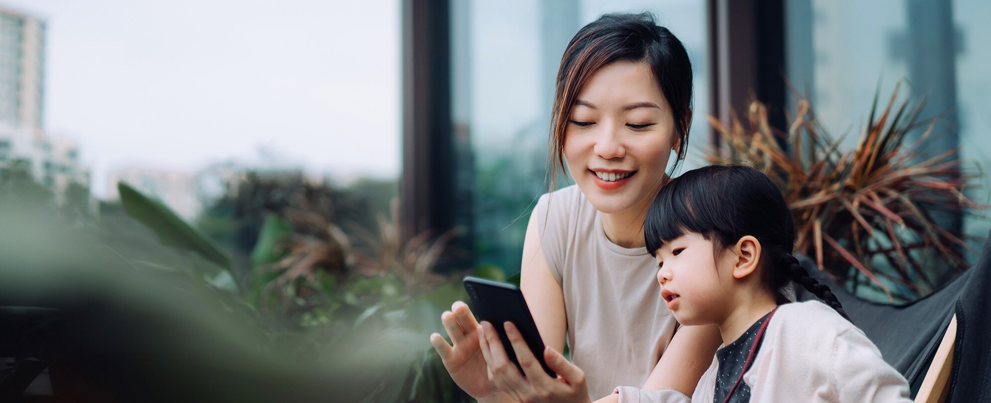 A mother and child sitting and looking at a cellphone. 