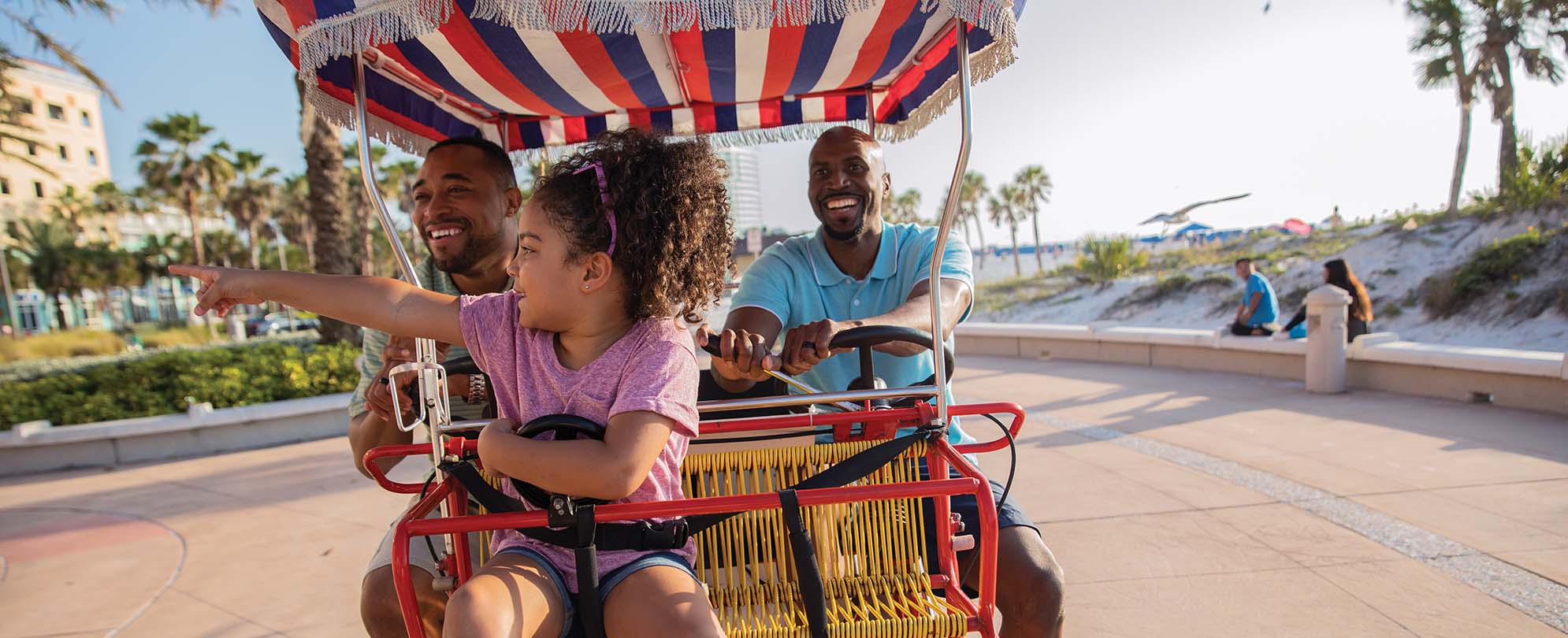 A family of three having fun on a boardwalk buggy. 