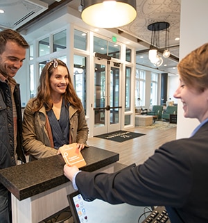 A smiling couple greets a WorldMark by Wyndham associate at the front desk of WorldMark Portland Waterfront Park in Portland, Oregon.