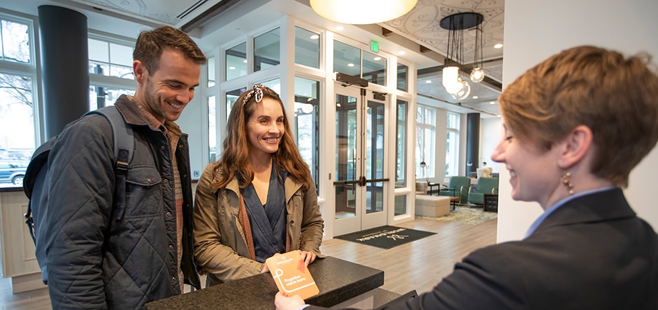 A smiling couple greets a WorldMark by Wyndham associate at the front desk of WorldMark Portland Waterfront Park in Portland, Oregon.