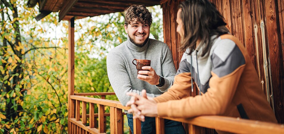 Two men standing by the balcony of a Club Pass resort cabin.